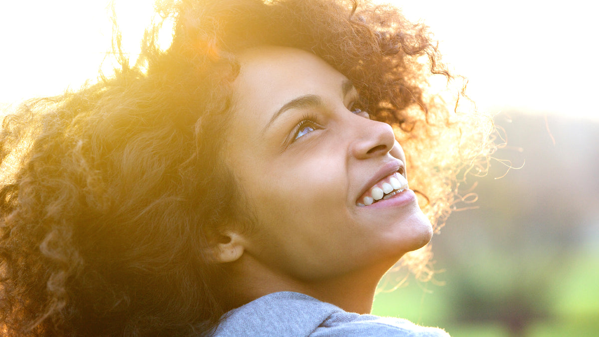 black woman with great skin looking up at sunset