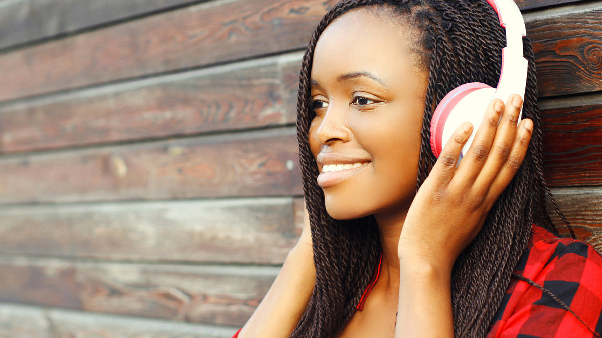 beautiful black girl leaning against wall with headphones