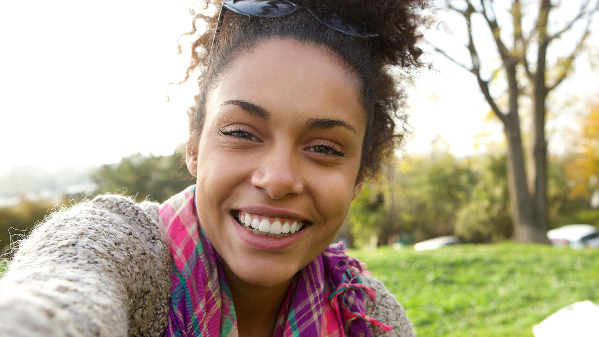 beautiful black woman laughing at camera outside in fall