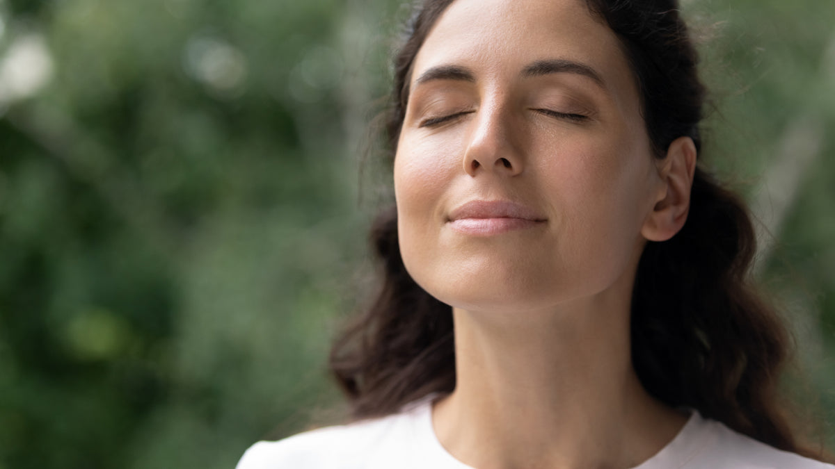 brunette woman eyes closed outside looking content