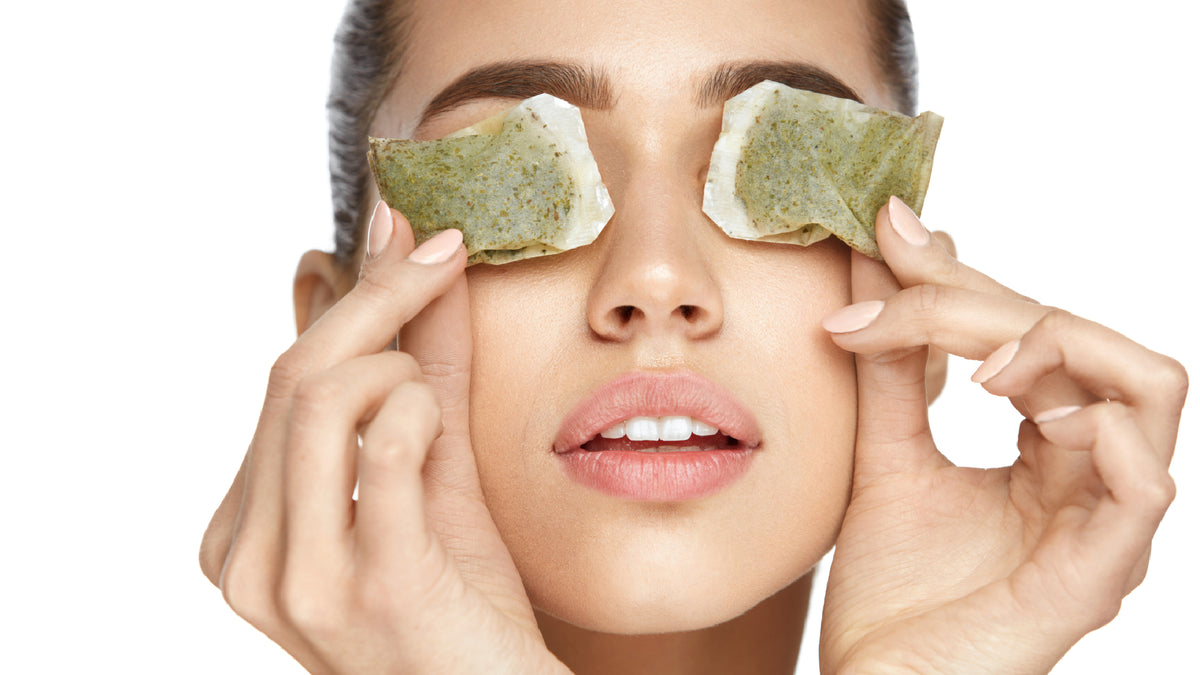 young white woman with green tea bags over eyes
