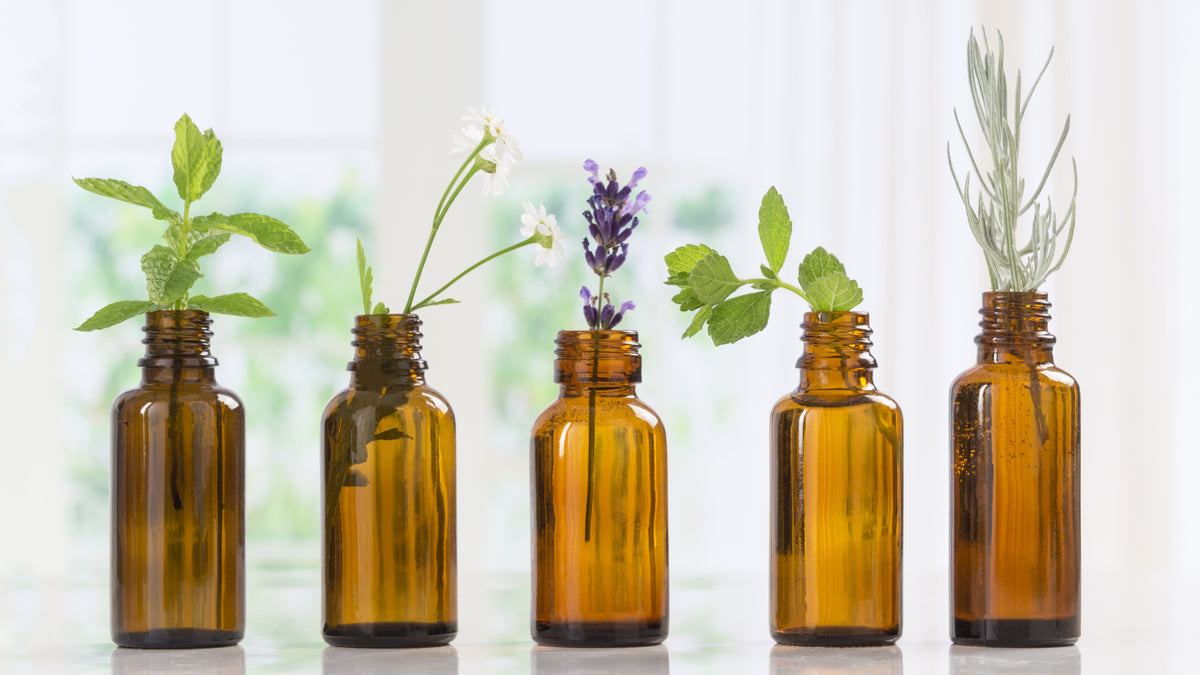 five bottles of essential oils with herbs