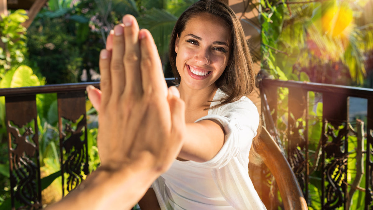 young brunette woman high fiving to camera