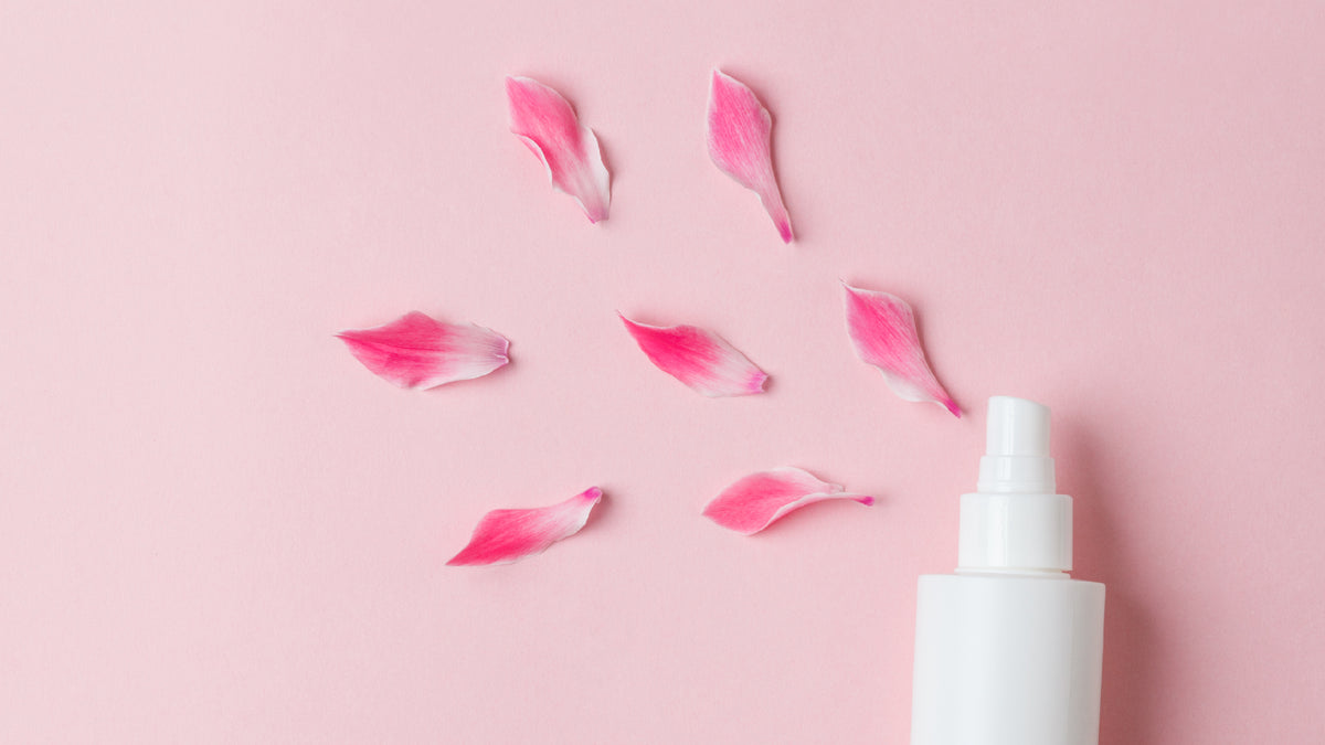 face mist spraying flower petals on pink background