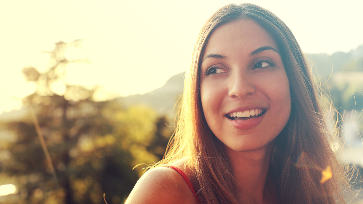 young brunette woman smiling outside at sunset