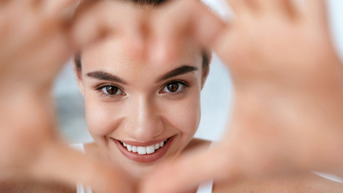 close-up of brunette girl making heart shape with hands