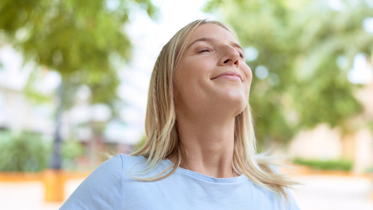 blonde with head in the air outside smiling