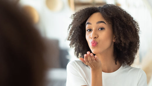 young black woman blowing kiss to herself in mirror