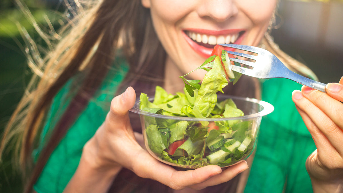 close-up of brunette woman smiling and eating salad