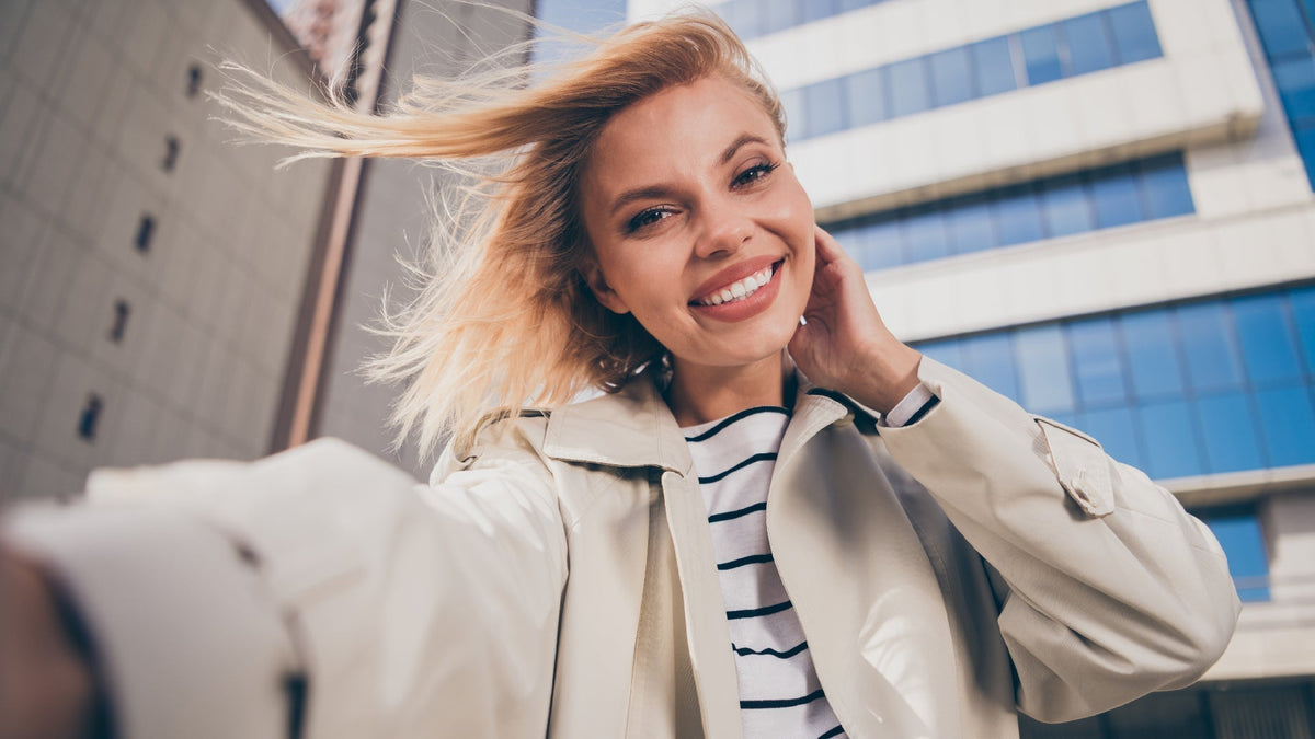 young blonde woman taking selfie in city
