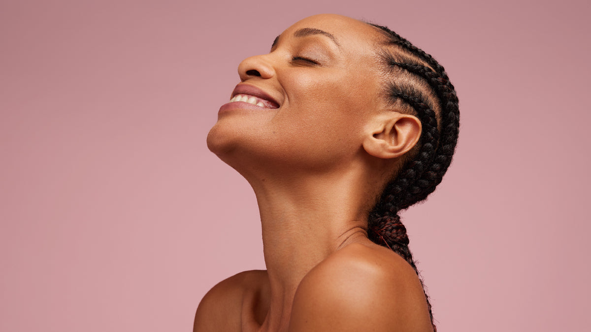 beautiful black woman with braids smiling with eyes closed and great skin
