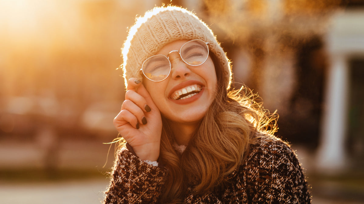 girl in glasses at sunset wearing beanie and laughing