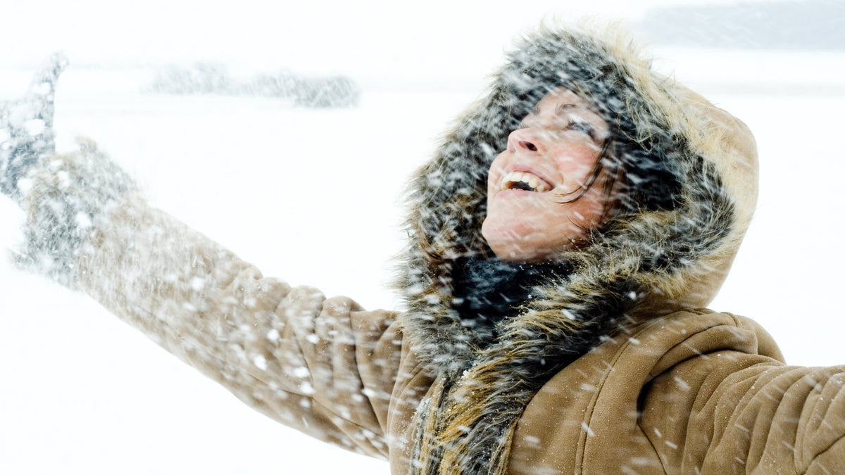 young woman wrapped up outside enjoying snowfall