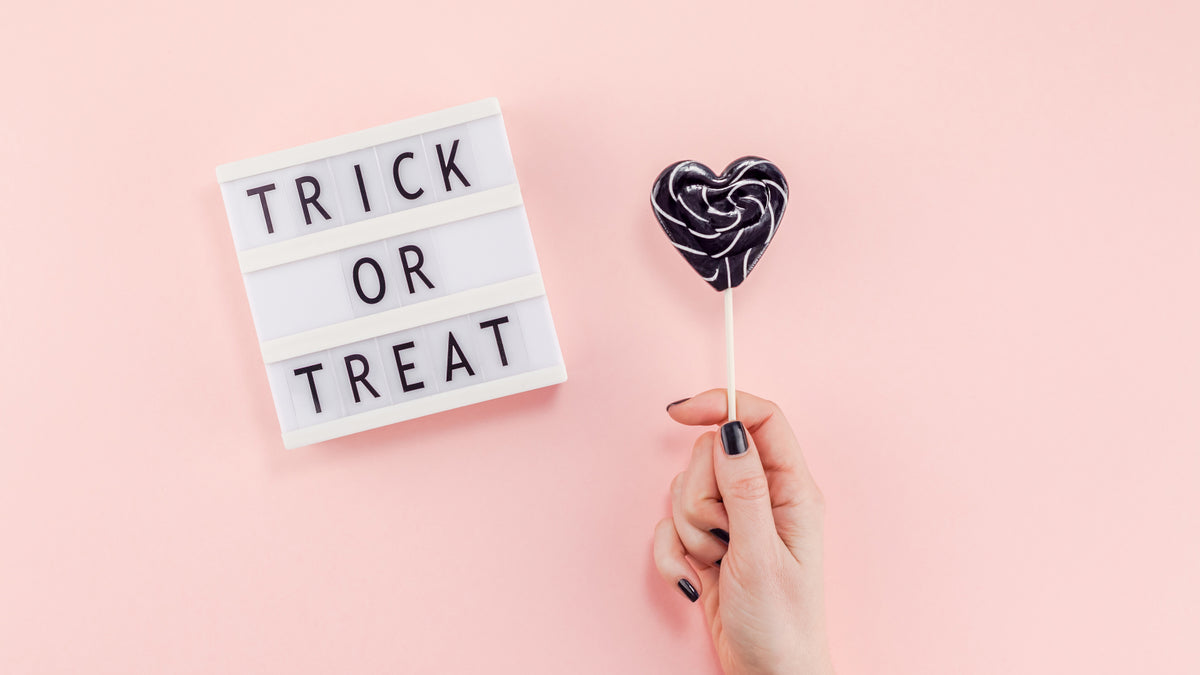 Lollipop on pink background next to trick or treat sign