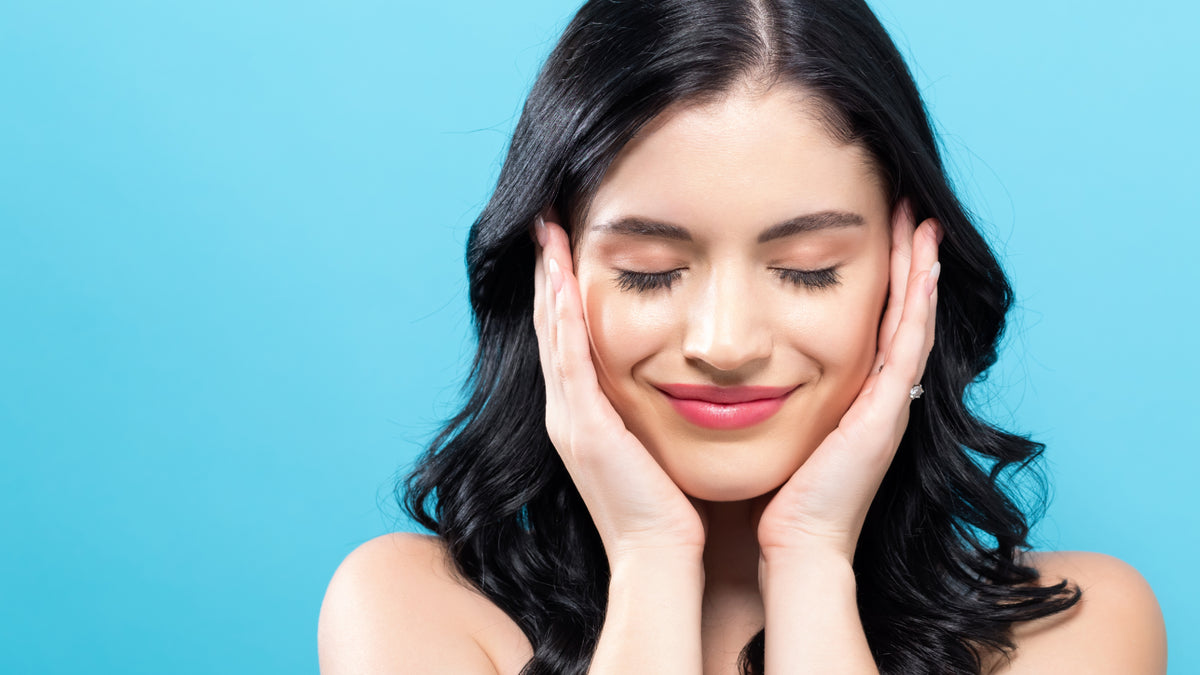 girl with black hair holding face and smiling