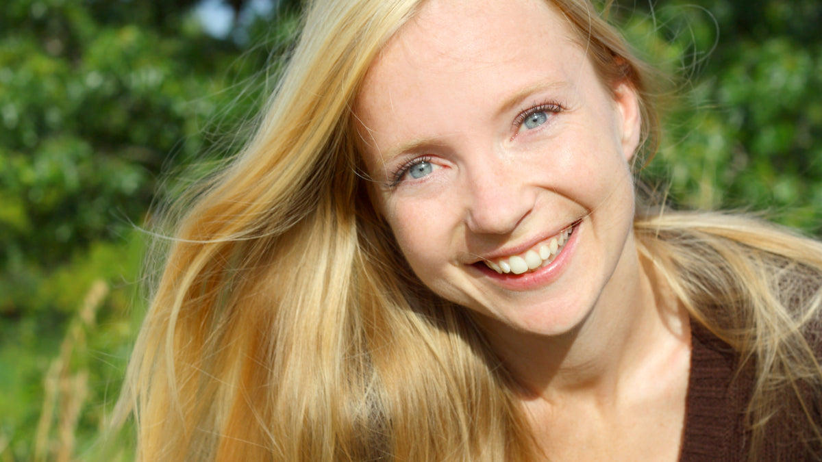 young blonde woman outside smiling with great skin