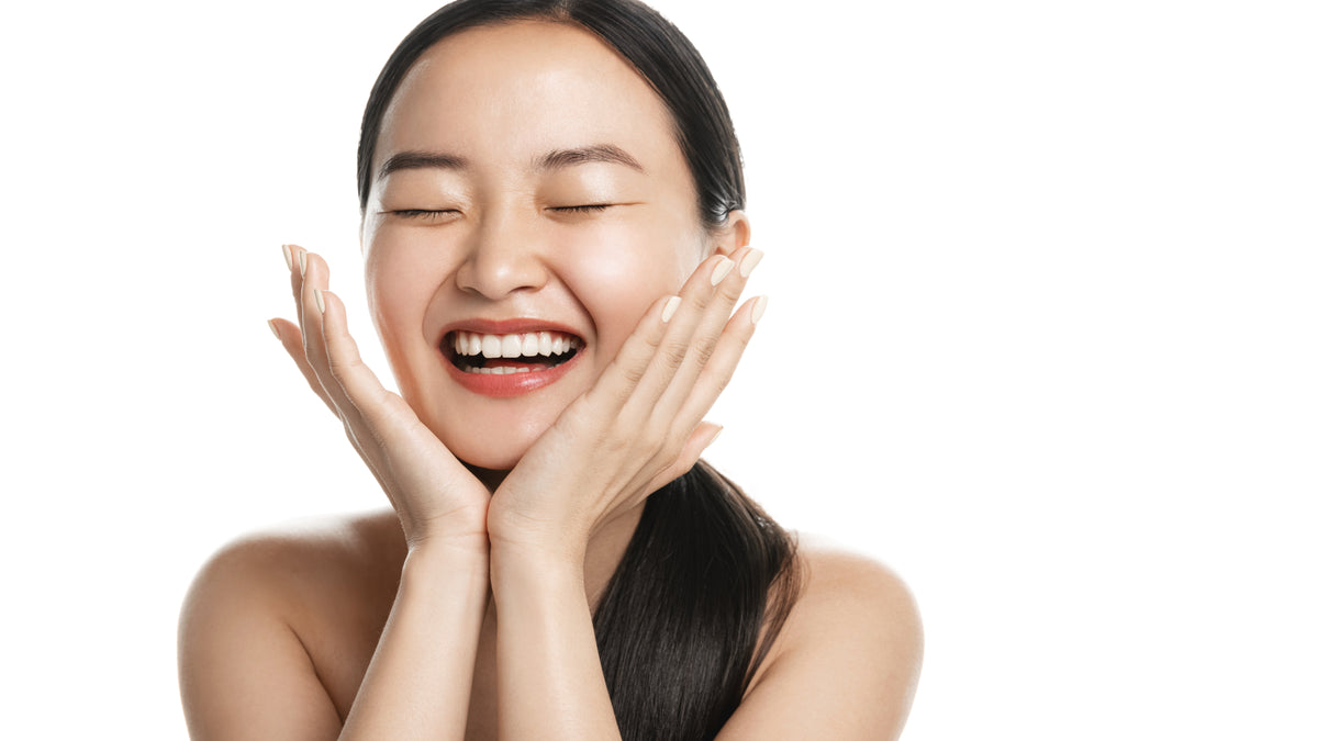 Asian girl with great skin smiling and touching face