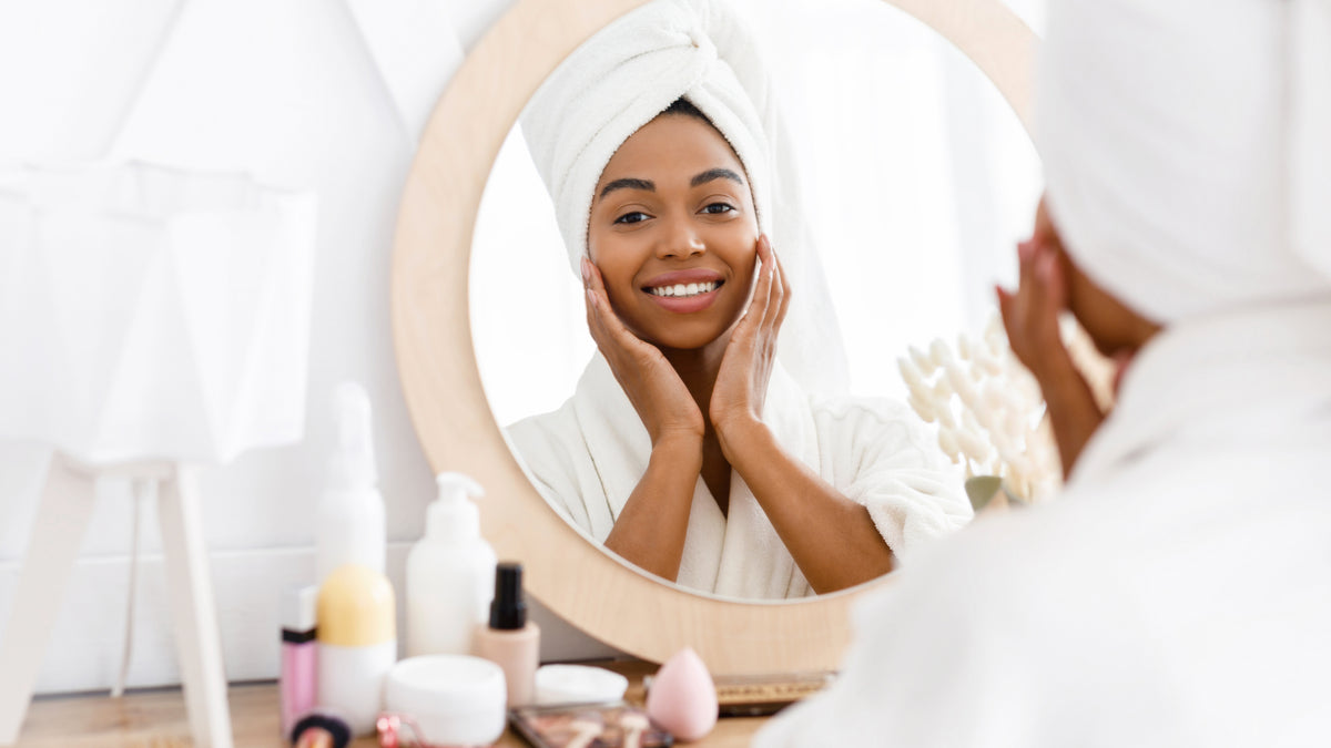 beautiful black girl looking in mirror and touching her skin