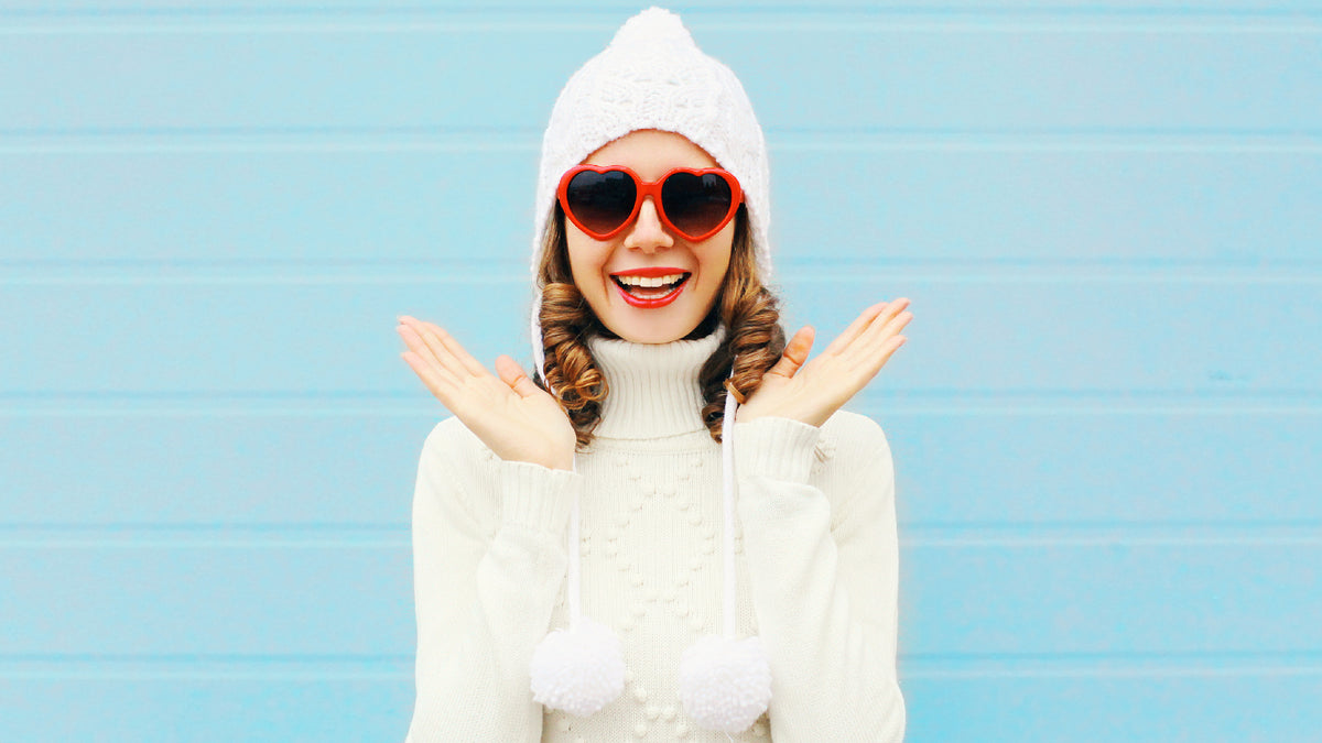 white girl in winter clothes smiling in front of blue brick wall