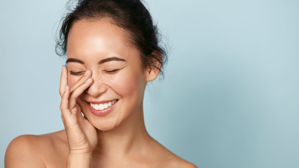 woman with beautiful skin touching face and smiling