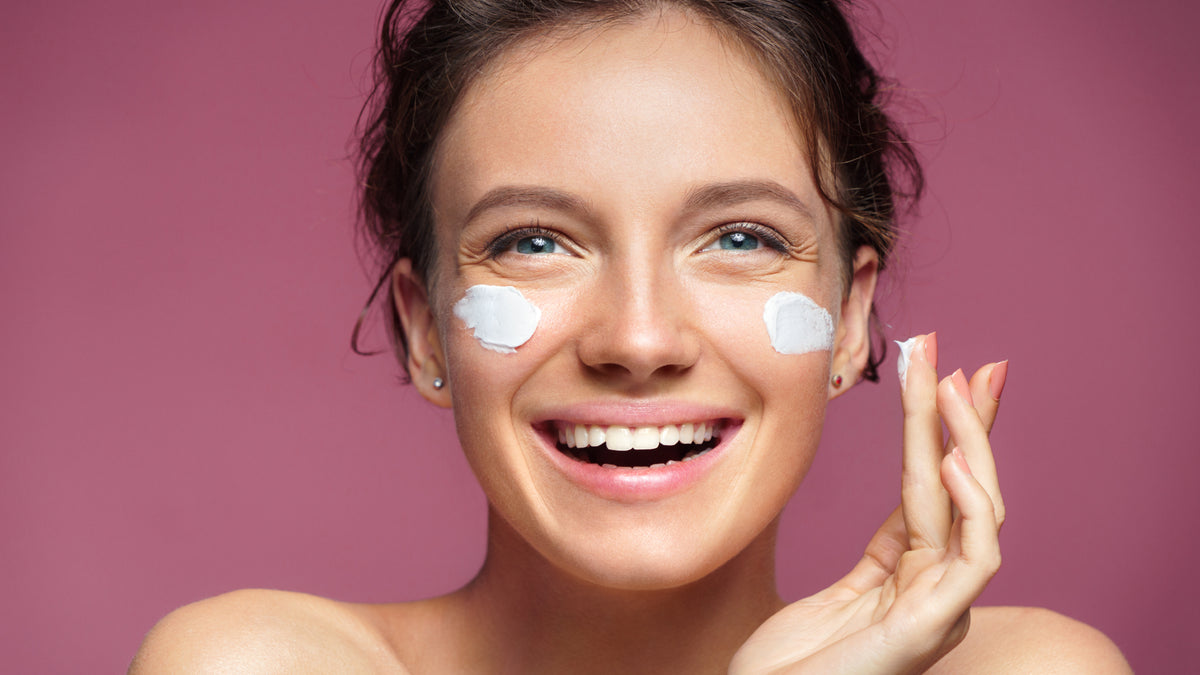 white woman laughing while applying face cream
