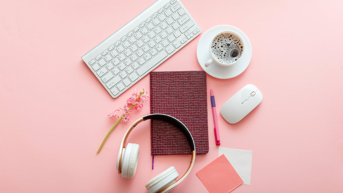 laptop, coffee and other desk supplies on pink background