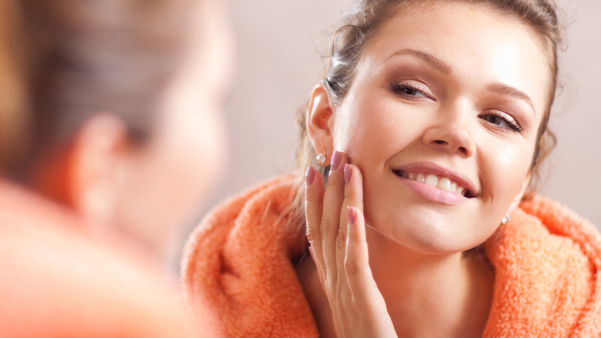 brunette girl touching face looking in the mirror
