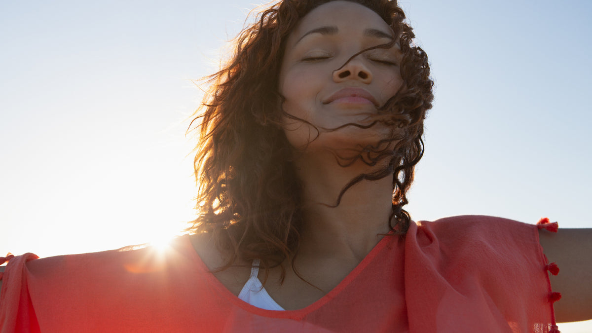 young woman smiling at dusk, with sun behind her