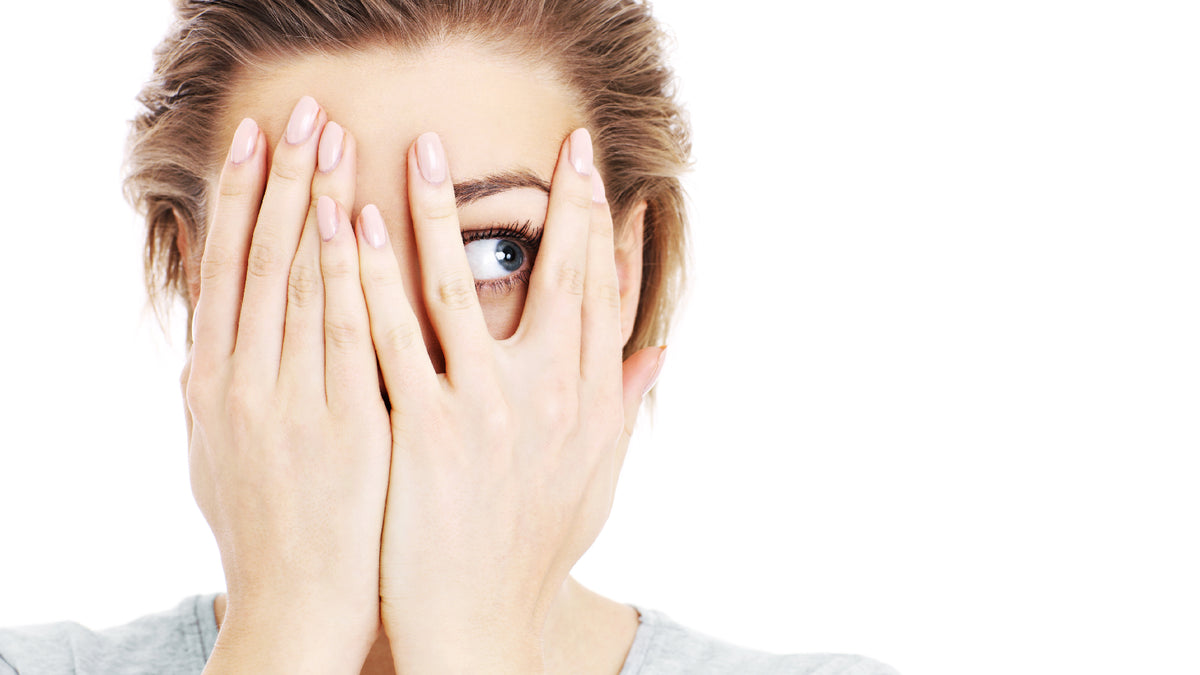 white girl hiding most of face with hands, on white background
