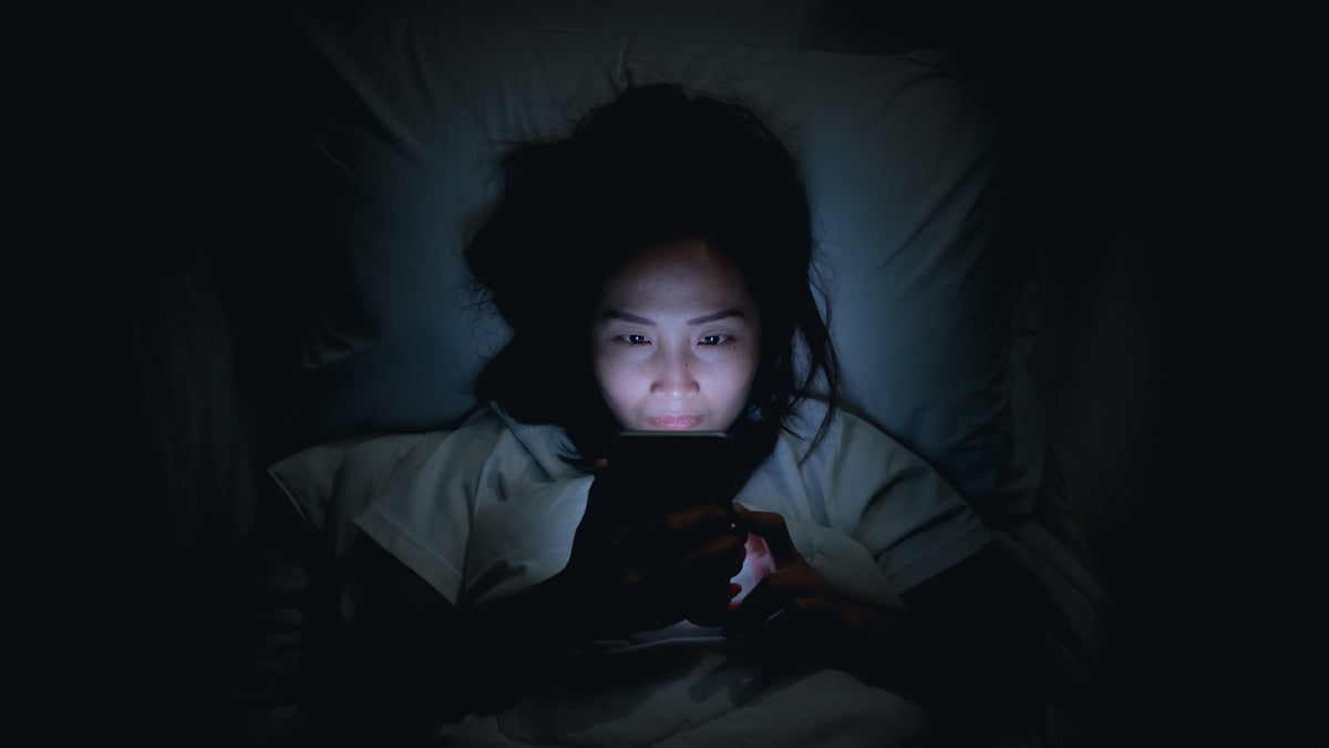 girl lying in bed checking phone