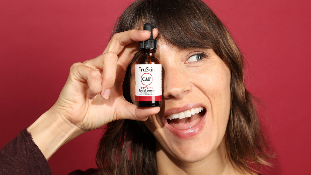 brunette woman holding truskin caffeine facial serum