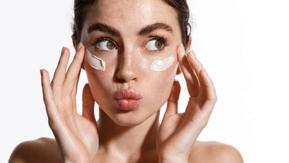 white girl with sunscreen on cheeks blowing kiss and touching face