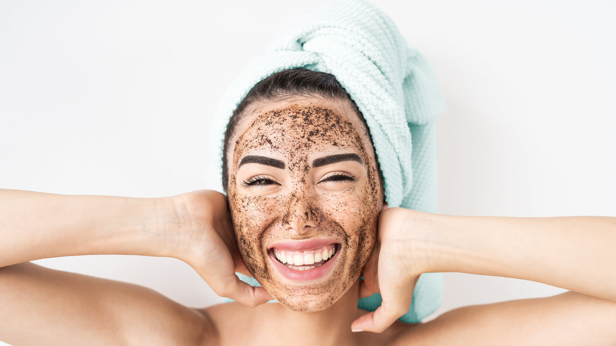 brunette young woman with towel on head and face scrub 
