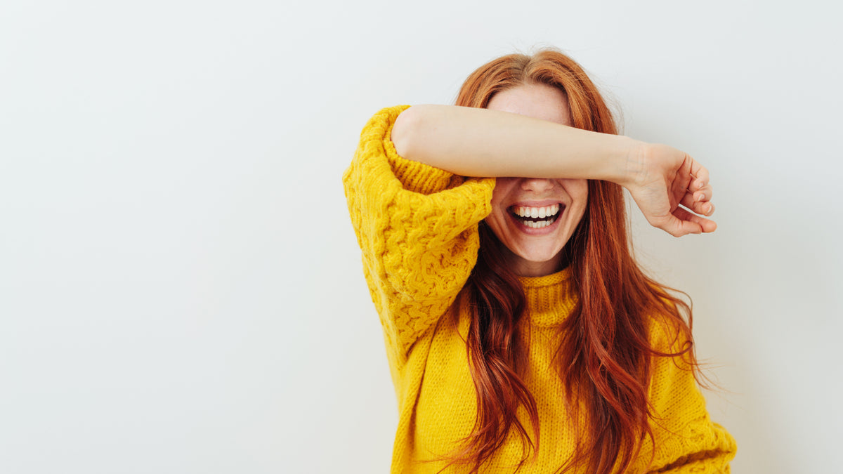 Redhead girl laughing and covering her eyes with her arm