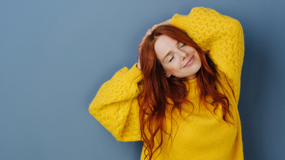 redhead woman looking happy and relaxed on blue background