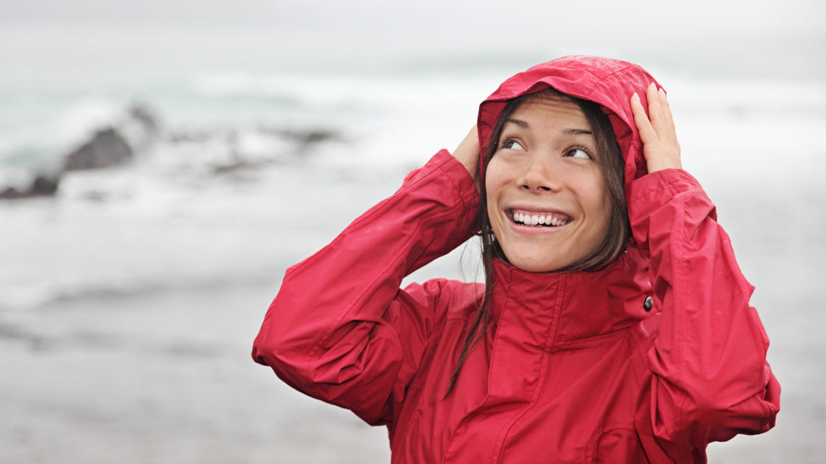 brunette woman outside in gray weather with hood up