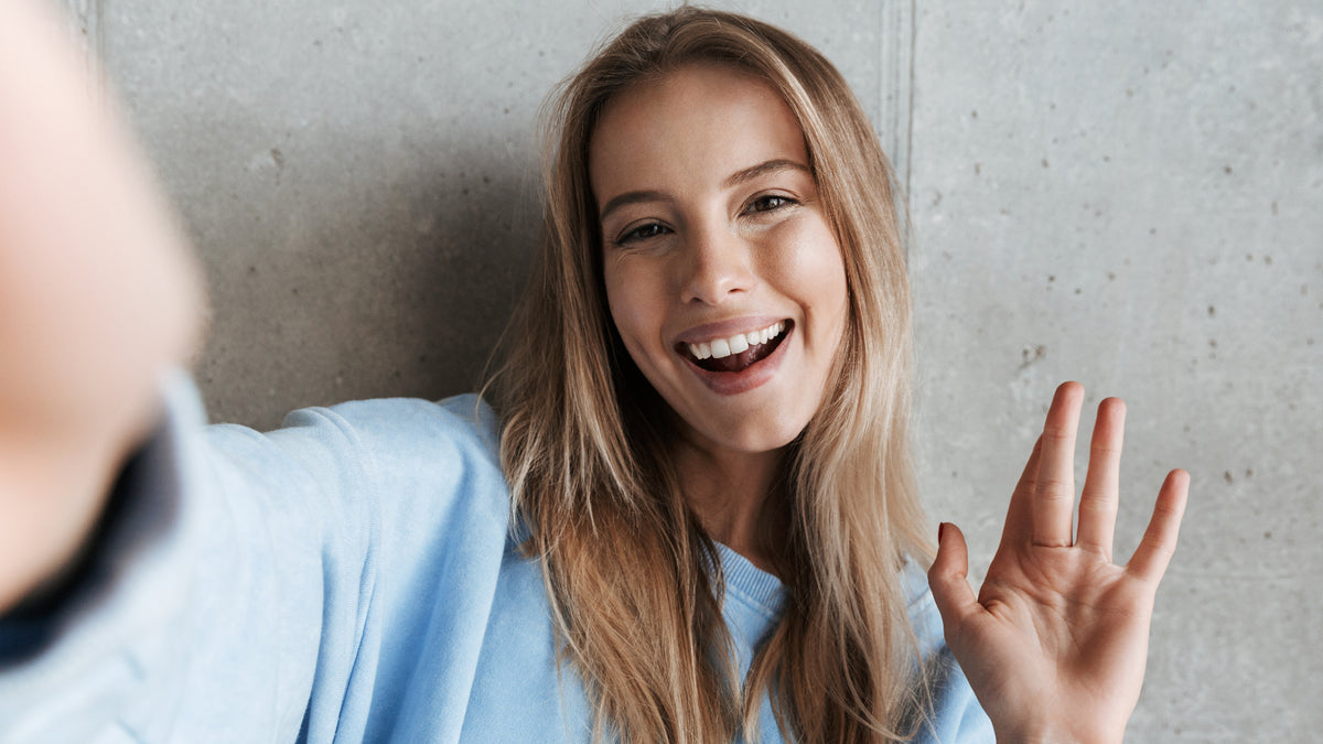 blonde girl with natural makeup taking a selfie and smiling