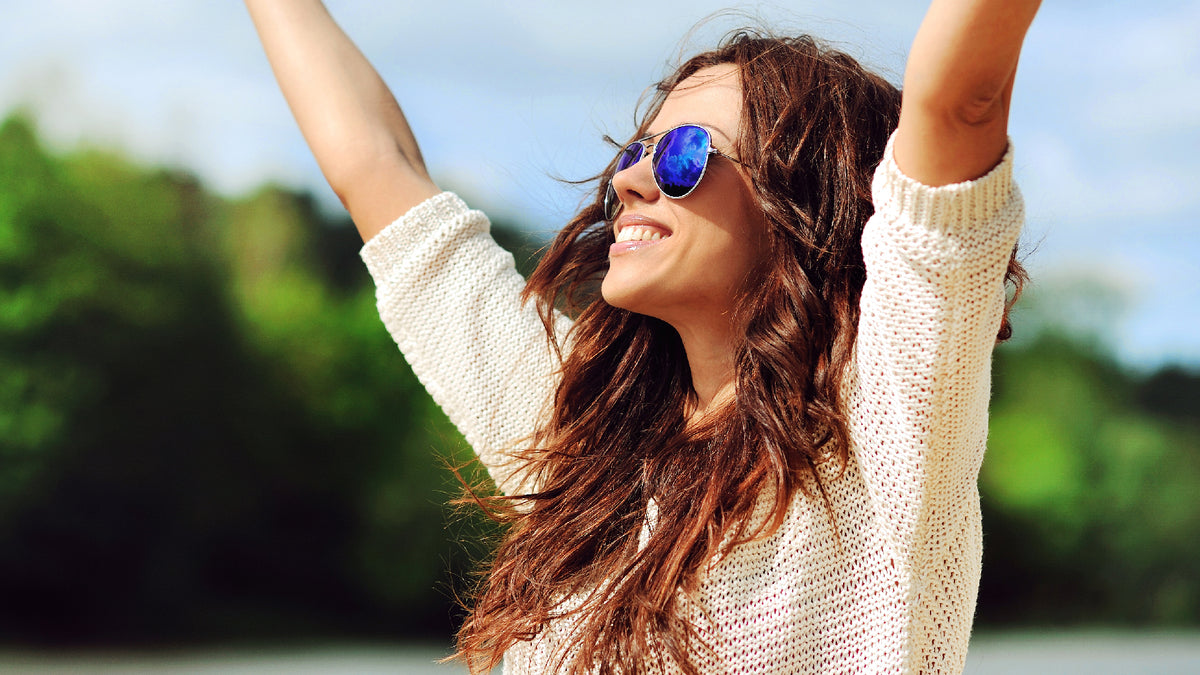 brunette girl looking happy outside, arms in the air