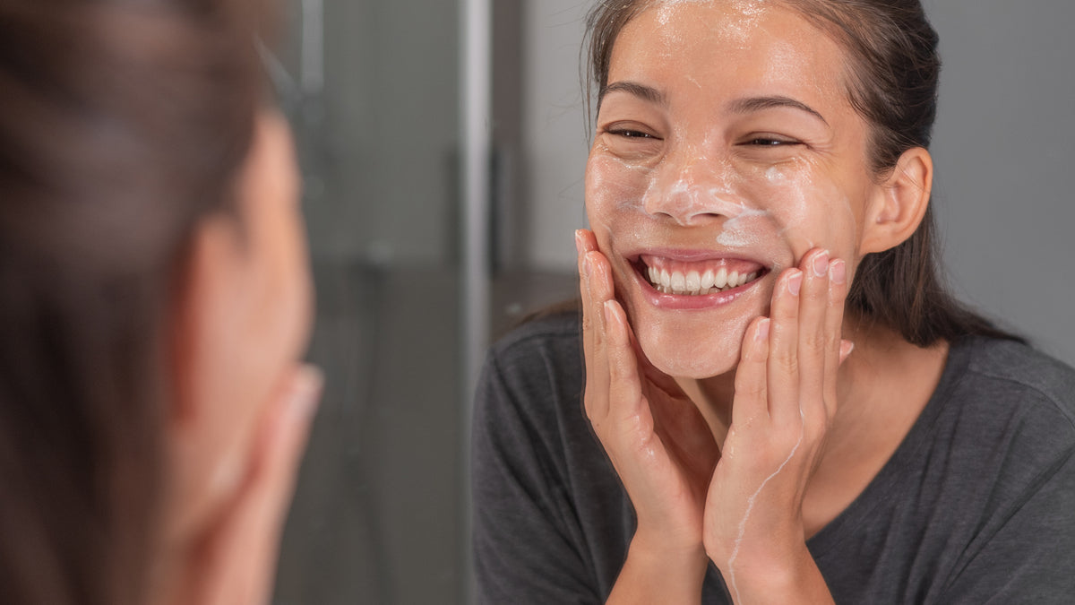brunette girl looking in mirror while applying skincare product