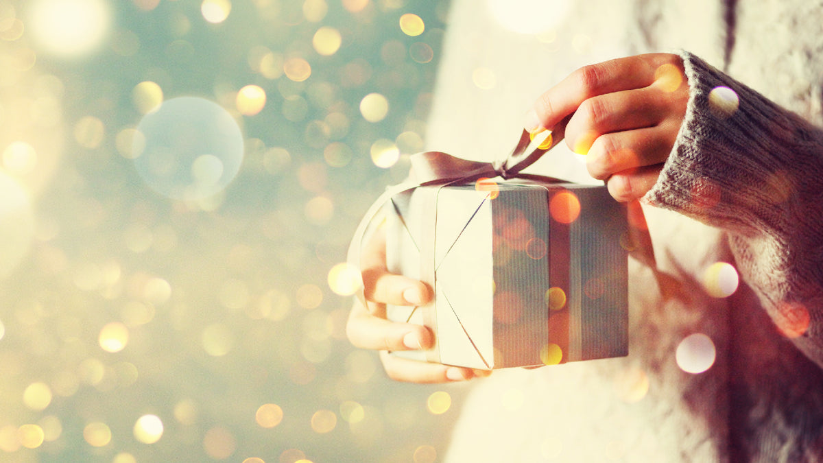 twinkly close-up of hands unwrapping holiday gift