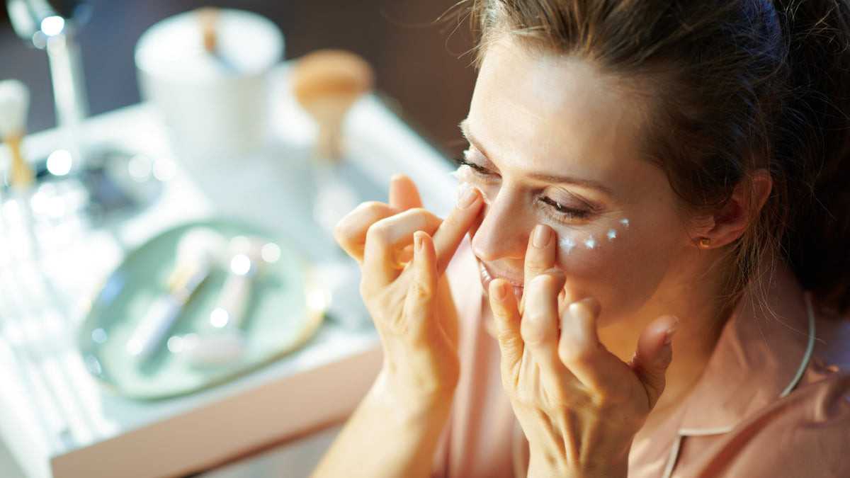 young brunette woman applying eye cream