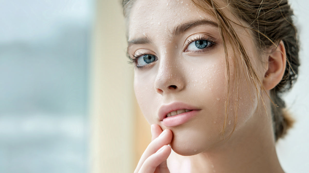 young brunette woman with drips of water on her face