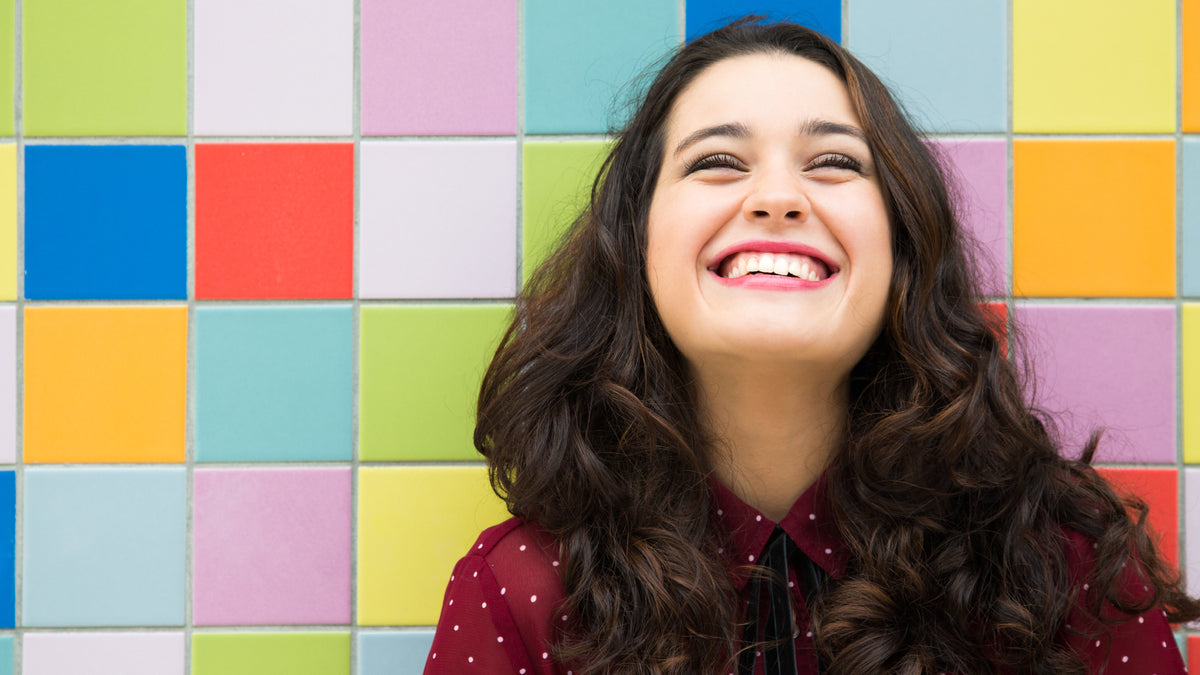 brunette girl laughing with colored tile background