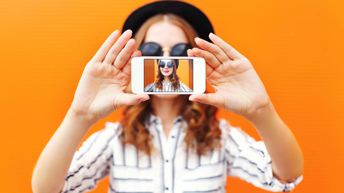 Redhead taking selfie showing phone to camera