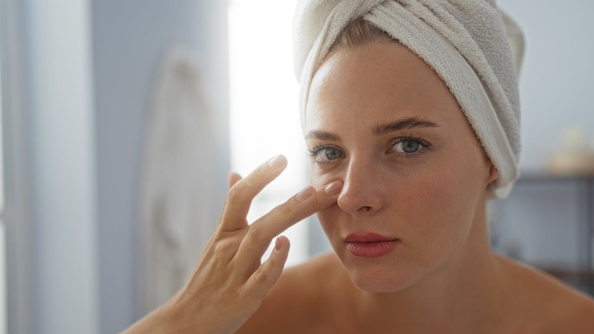 young woman applying moisturizer in the mirror