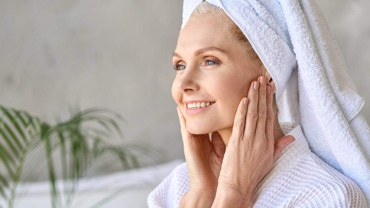 mature woman with amazing skin, applying skincare with towel on head