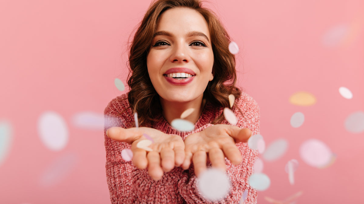 brunette girl celebrating on pink background