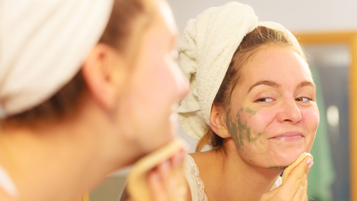 young blonde woman apply face mask in the mirror