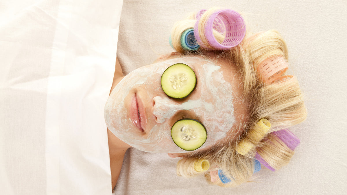 blonde woman lying on bed with cucumbers over eyes