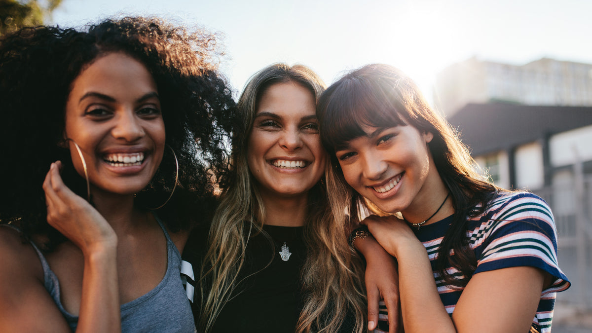 three girls outside laughing in sunshine